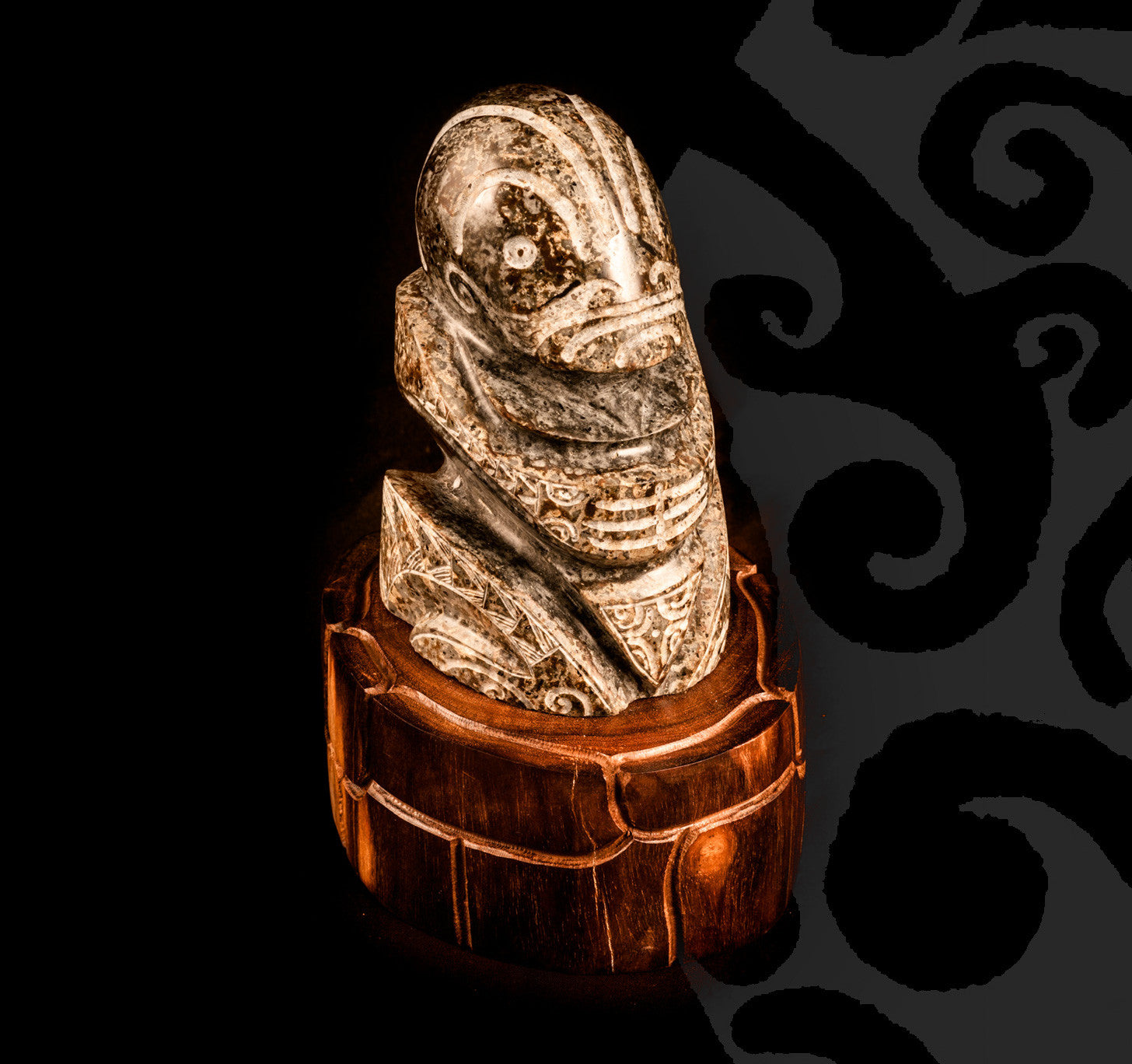 Tiki sculpted in stone on a wooden pedestal